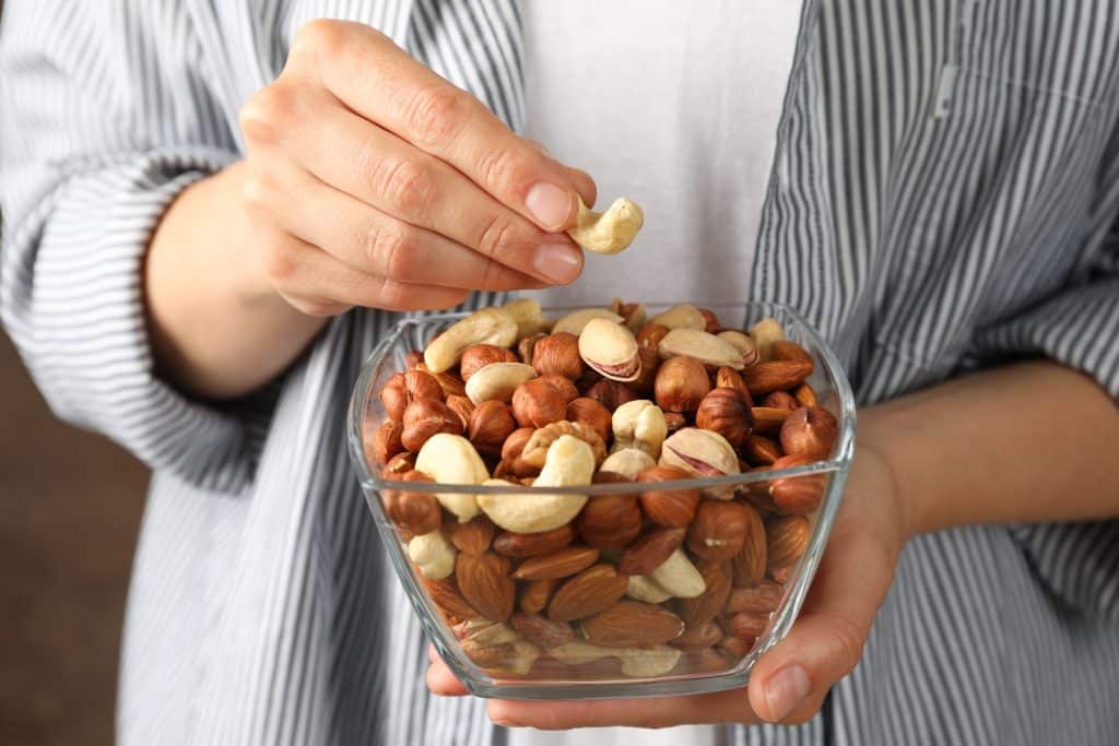 Woman hold bowl with different nuts. Healthy eating